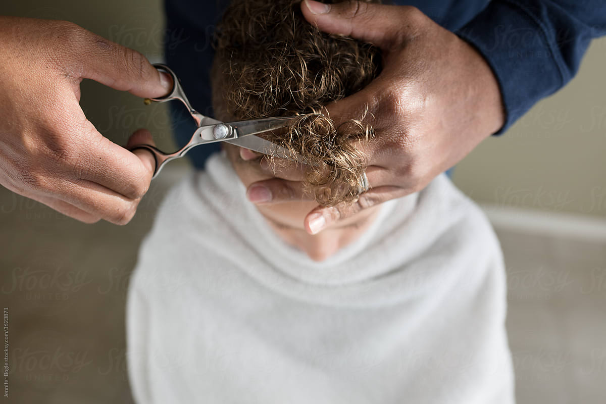 Closeup of scissors as father cuts son\'s curly hair