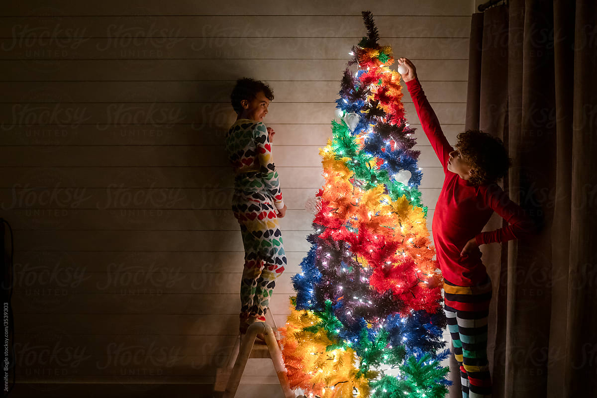 Siblings decorate tree in dark room