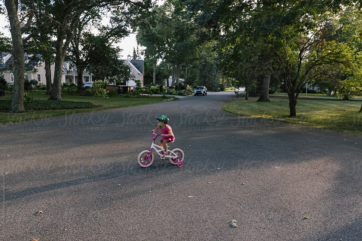Young Girl learning to ride bike with training wheels