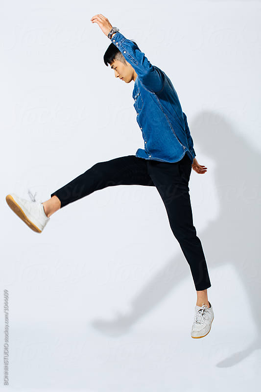 Jumping stylish asian man over white background.