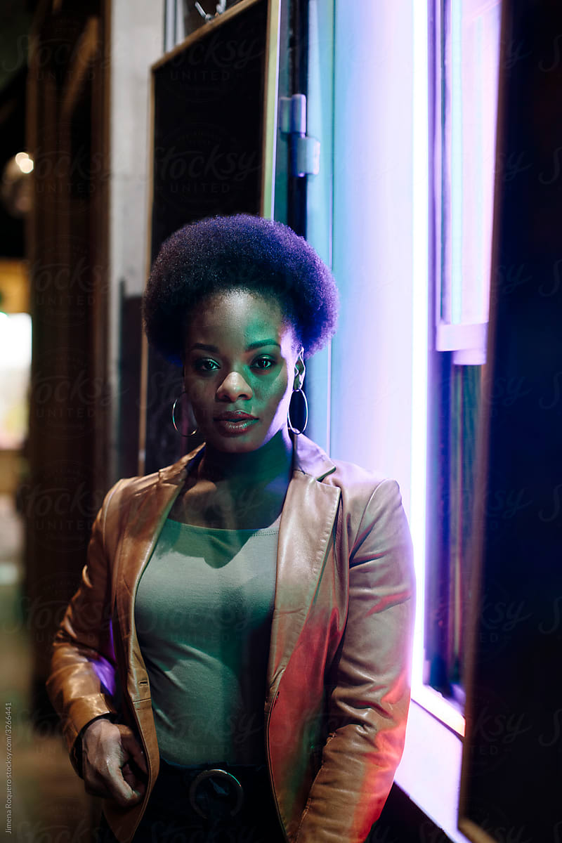 Woman with afro hair at night in the street looking at camera
