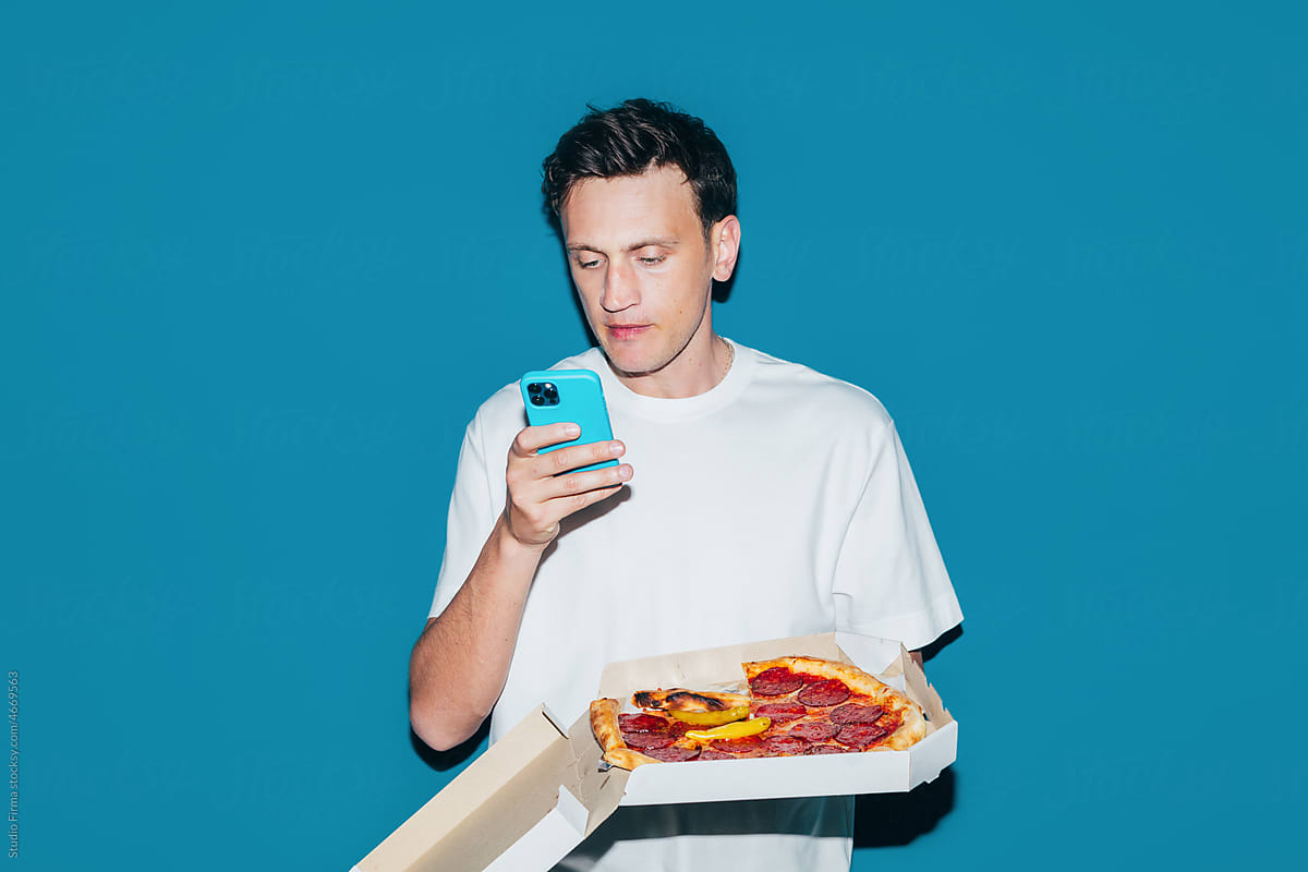 Man Holding Box with Pizza and Using Phone