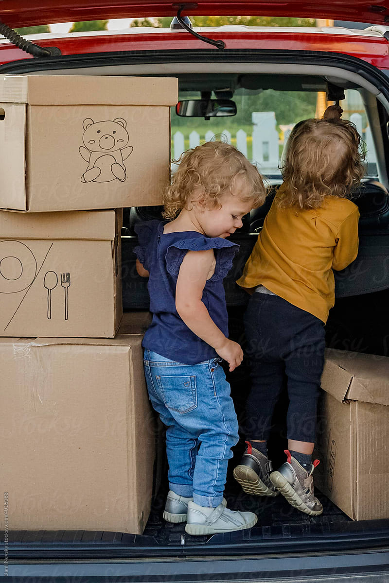Kids playing near boxes in car trunk