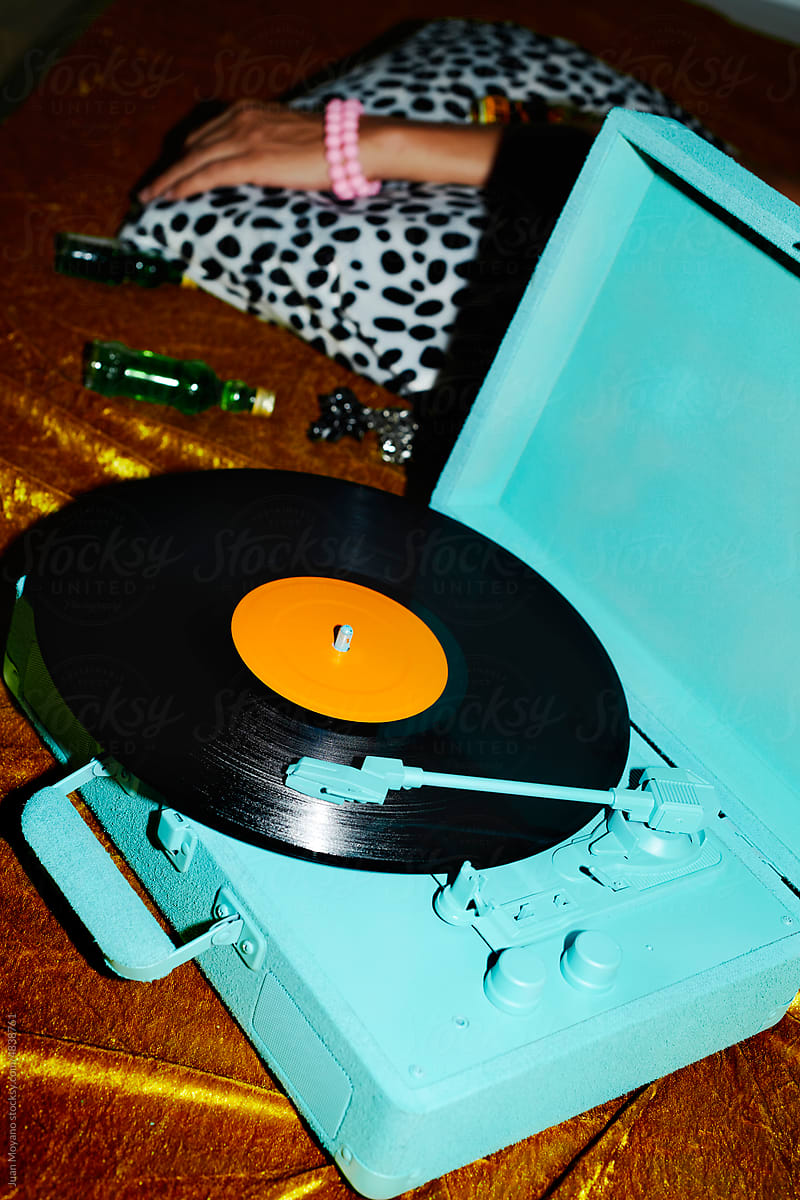 blue turntable playing a disc and man lying down on the bed