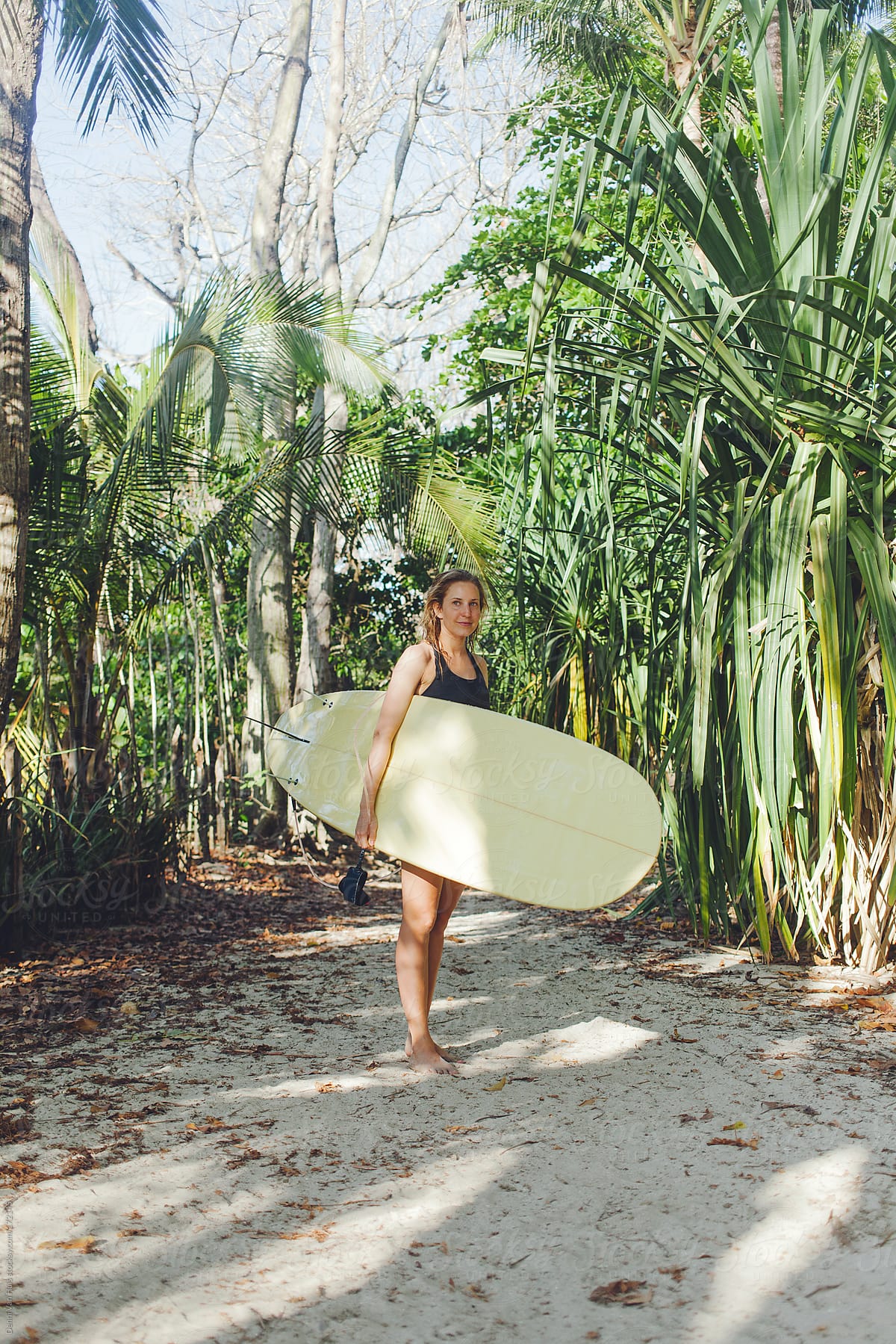 Heathy woman holding her surfboard on her way to the beach to go surfing.