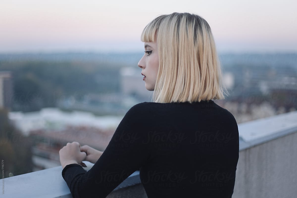 Beautiful blonde woman on the roof of the building during sunset