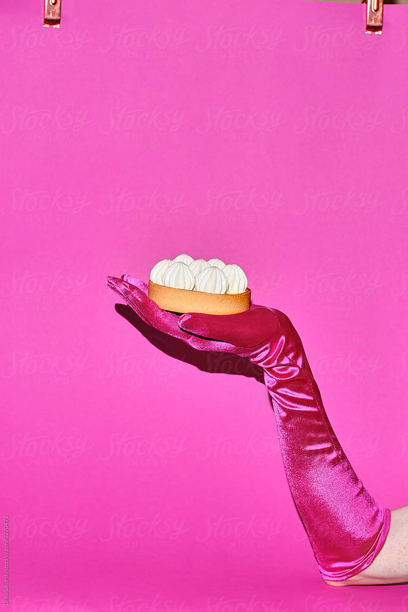 Luxurious dessert in a female hand on a pink background