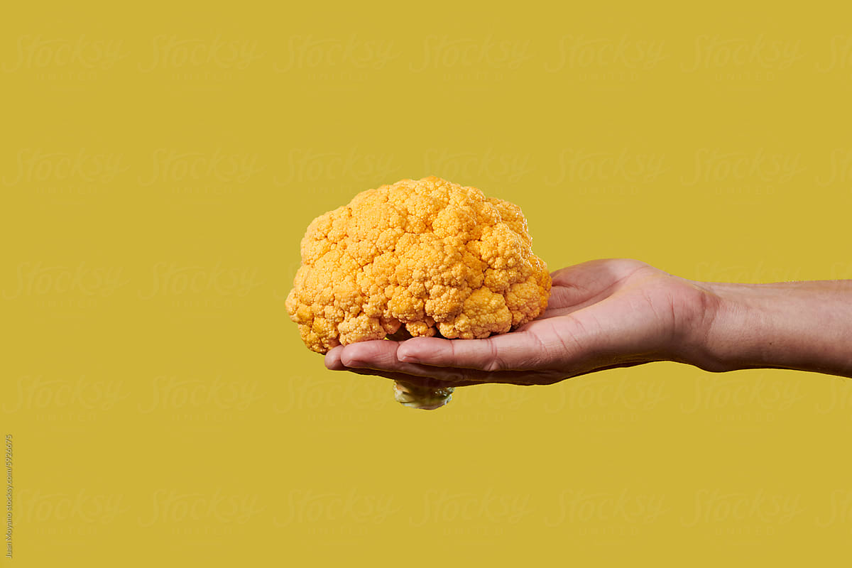man with an orange cauliflower in his hand