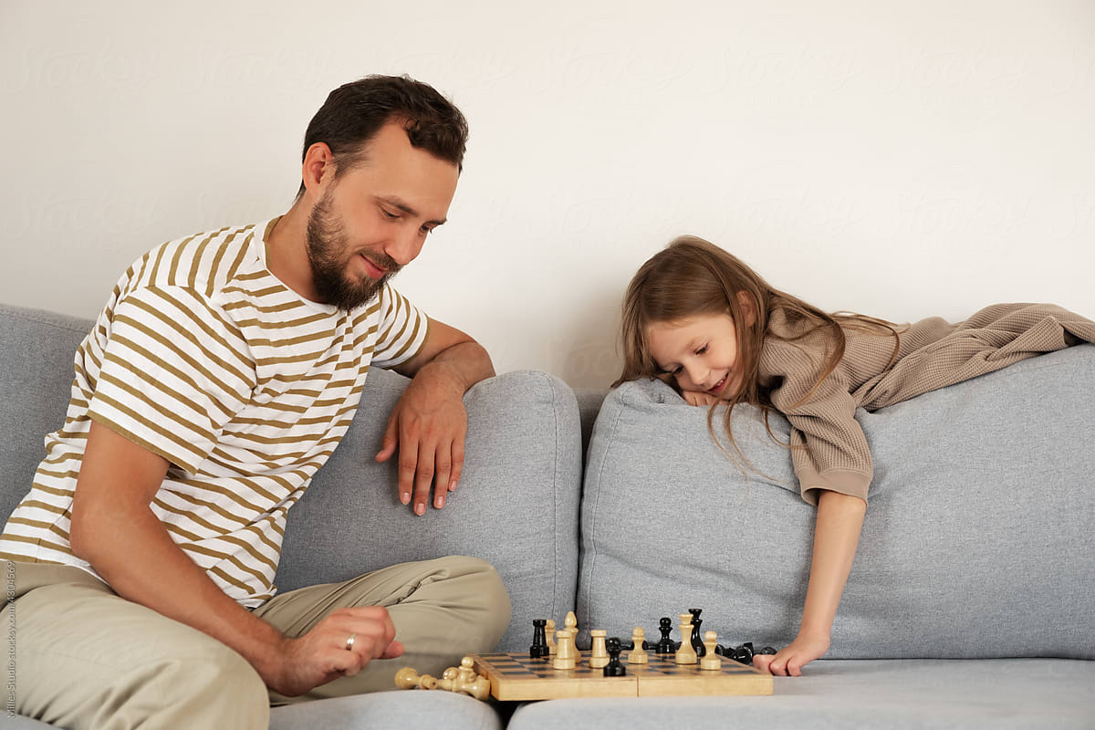 Glad father and daughter playing chess in living room
