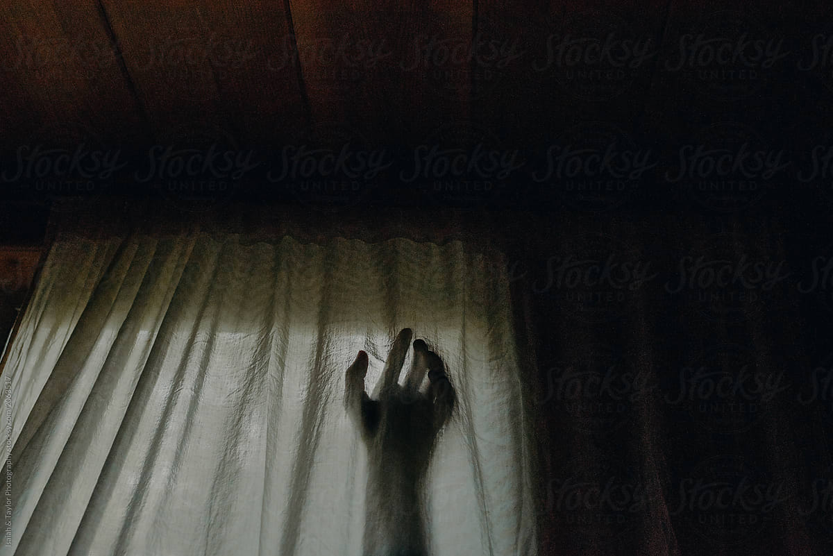 A shadowed silhouette of a person\'s hand reaching into a bedroom through a window