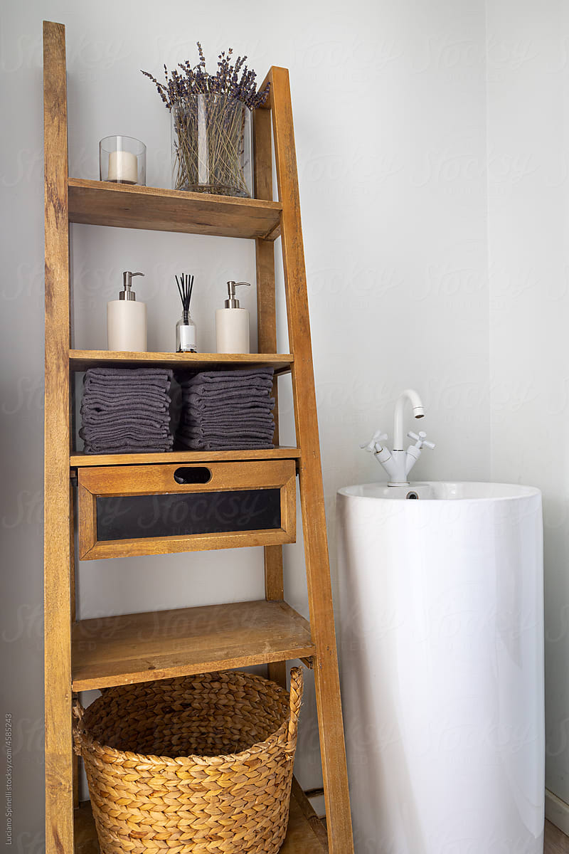 Wooden shelves with hygiene accessories near the sink in modern design