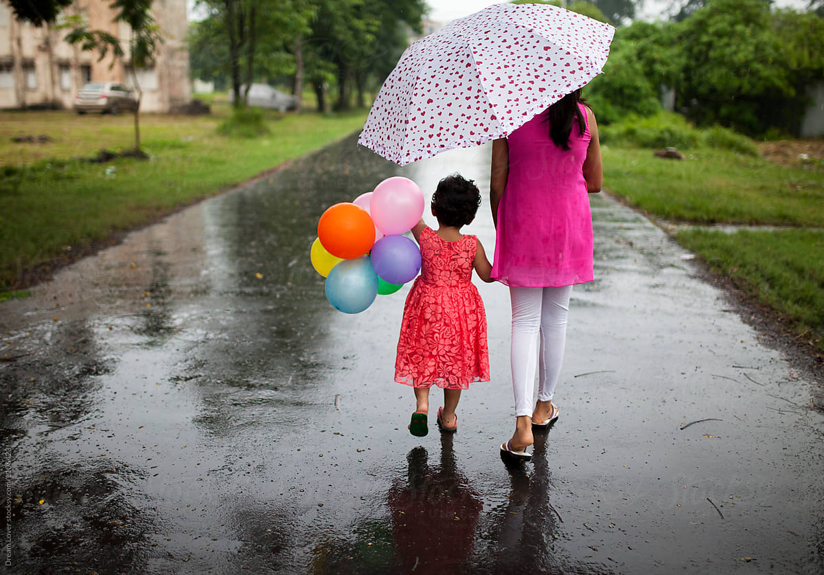 Elder sister with little girl under umbrella with balloon