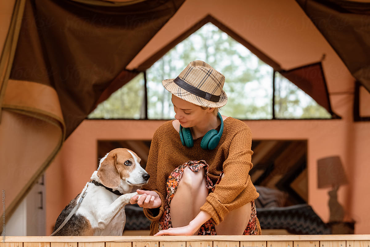 Woman shaking paw of dog on tent terrace