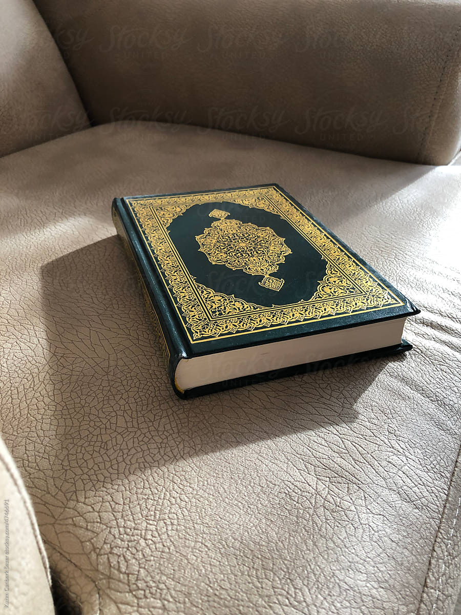 The holy Quran with green cover on gray chair