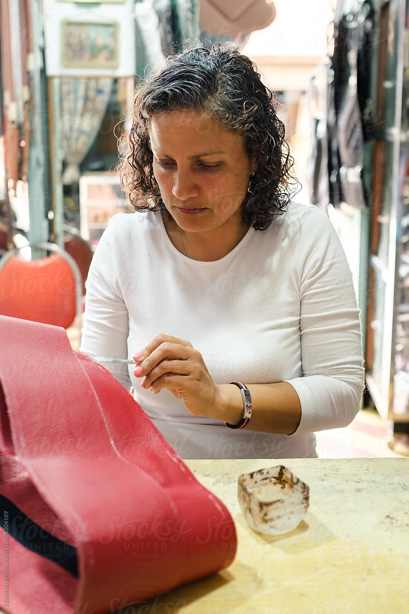Mature woman making a leather briefcase in workshop
