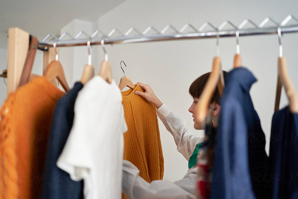 Woman choosing sweater at home