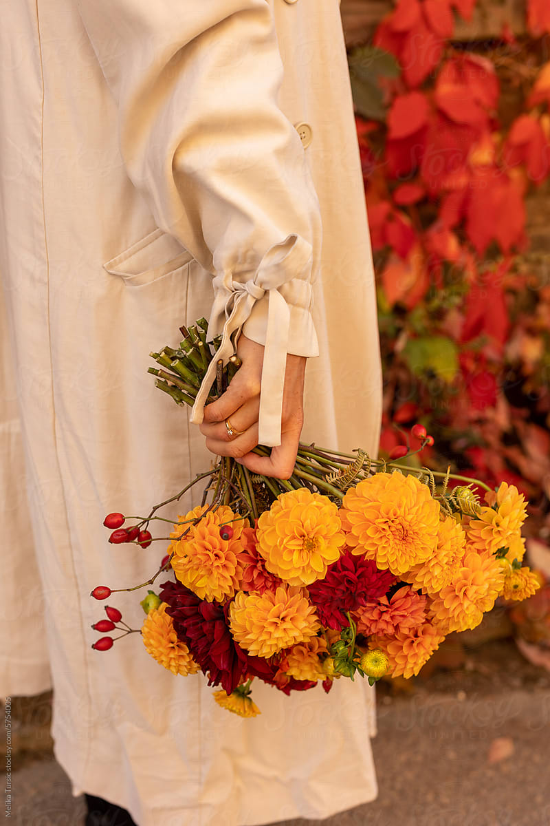 woman walking and holding autumn bouquet of flowers