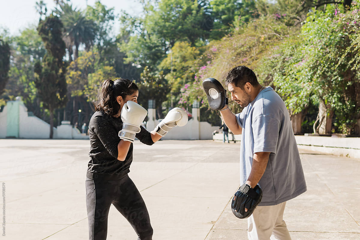 Personal trainer teaching boxing in a park.