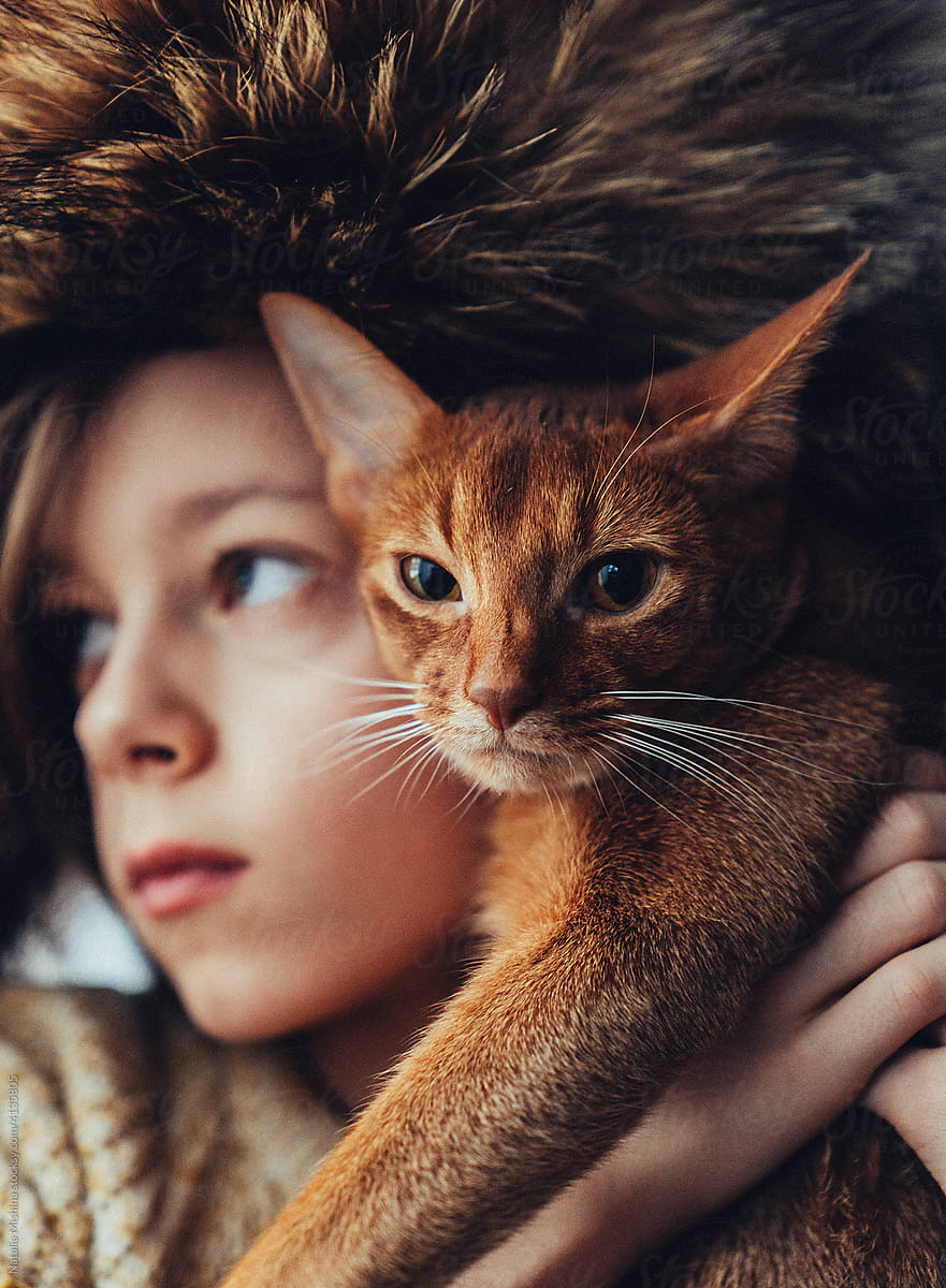 The cat is in the girl\'s arms.