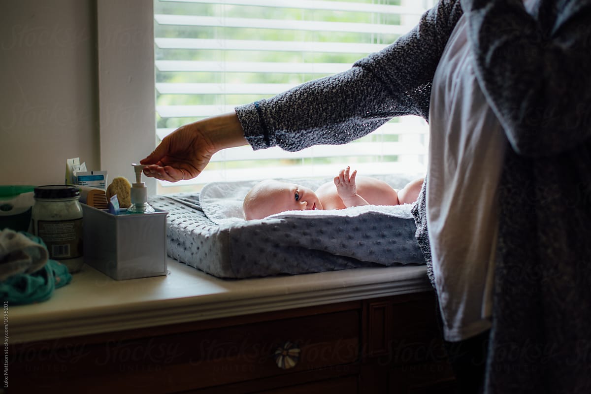 Mother Applying Hand Sanitizer Before Changing Newborn Baby Girl\'s Diaper