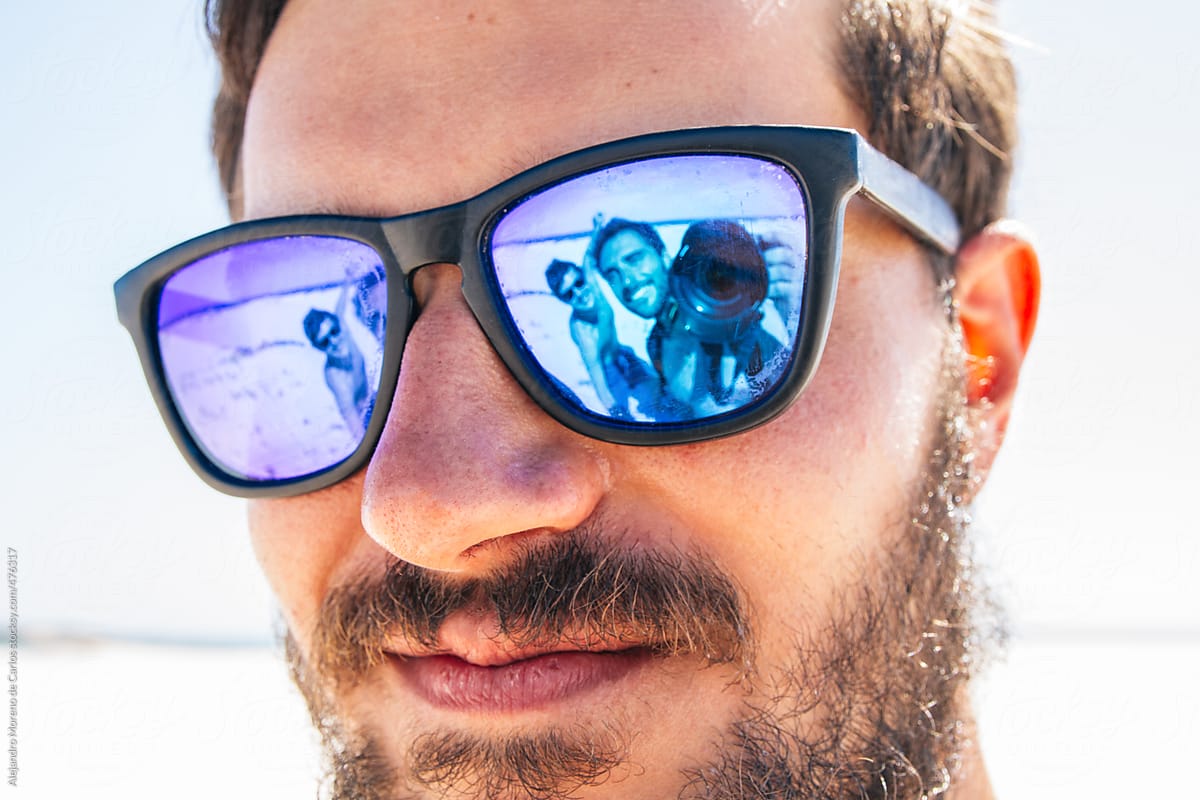 Young hipster man portrait with his happy friends showing on the reflection of his sunglasses