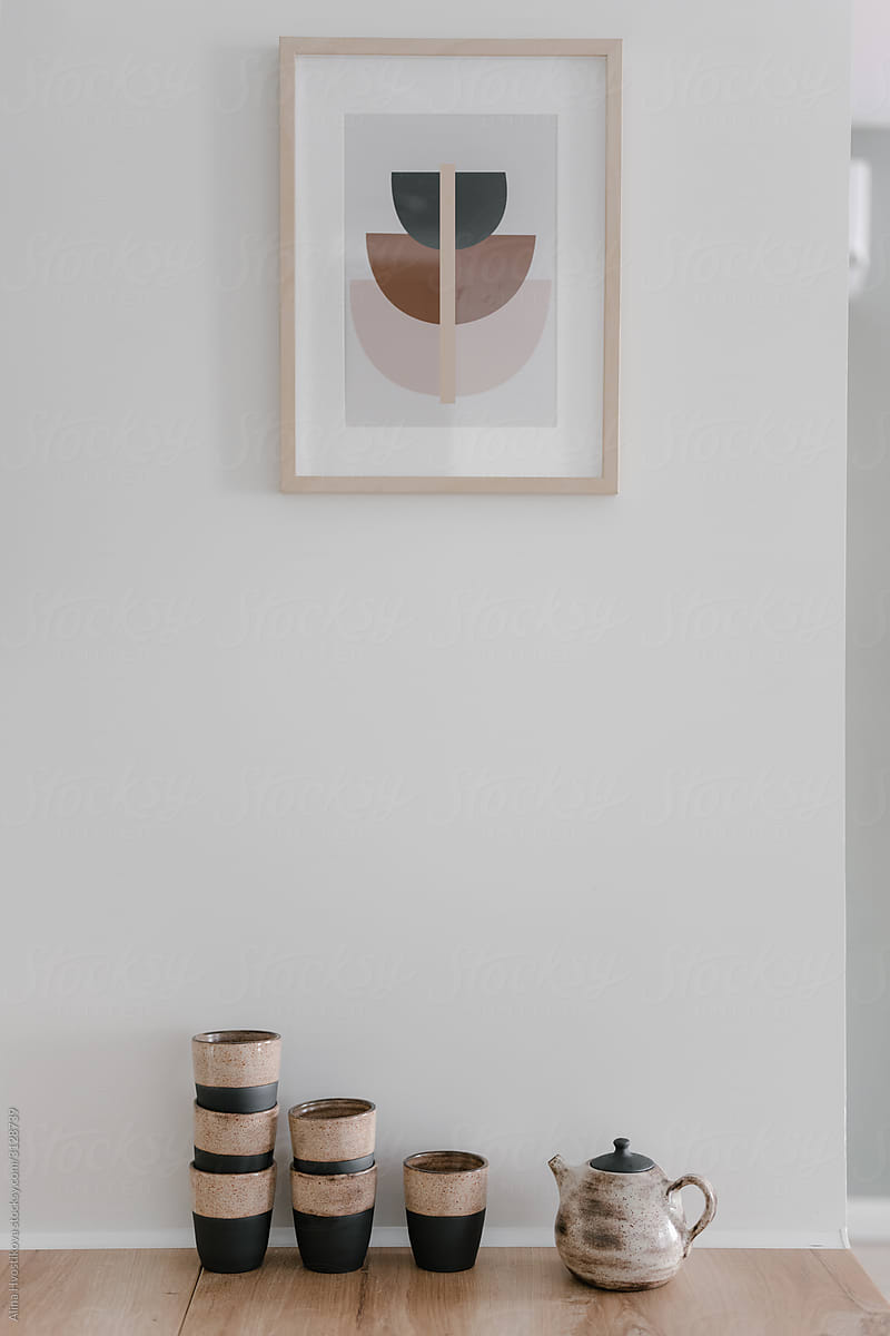 Crockery on wooden floor at white wall with painting