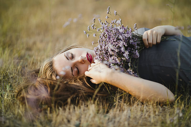 Beautiful Young Woman Lying On Grass And Holding Flower Bouquet By Jovana Rikalo Stocksy United 