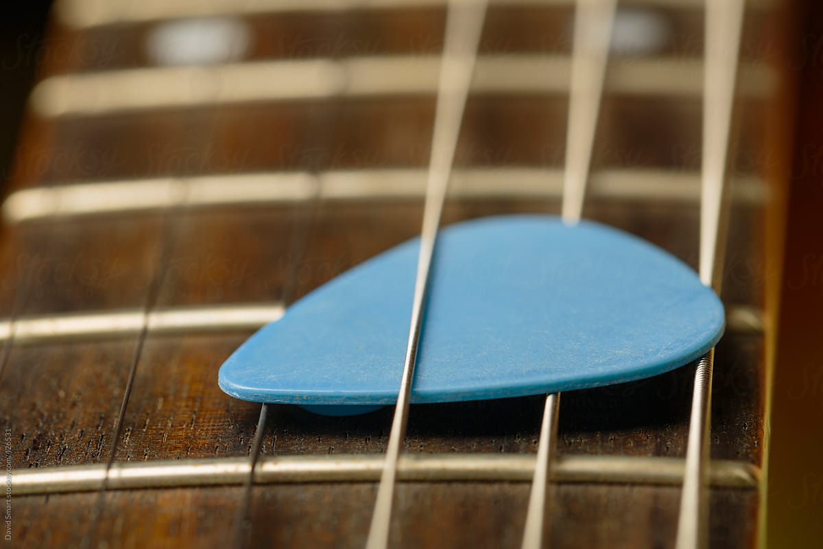 Blue guitar pick tucked between strings