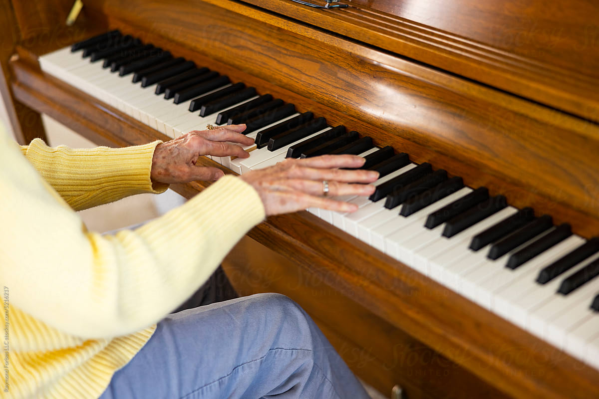 Happy Senior Citizen woman at Home playing wooden piano