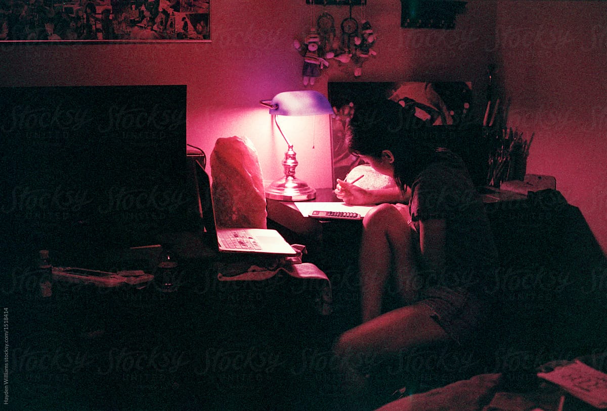 Girl studying at desk in dimly lit room