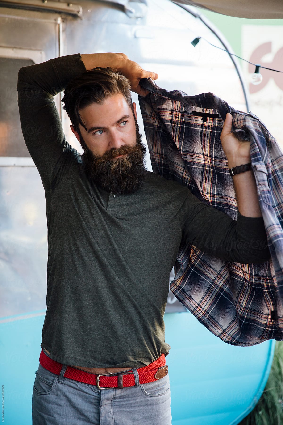 Handsome Young Man With Beard Putting on Flannel Shirt