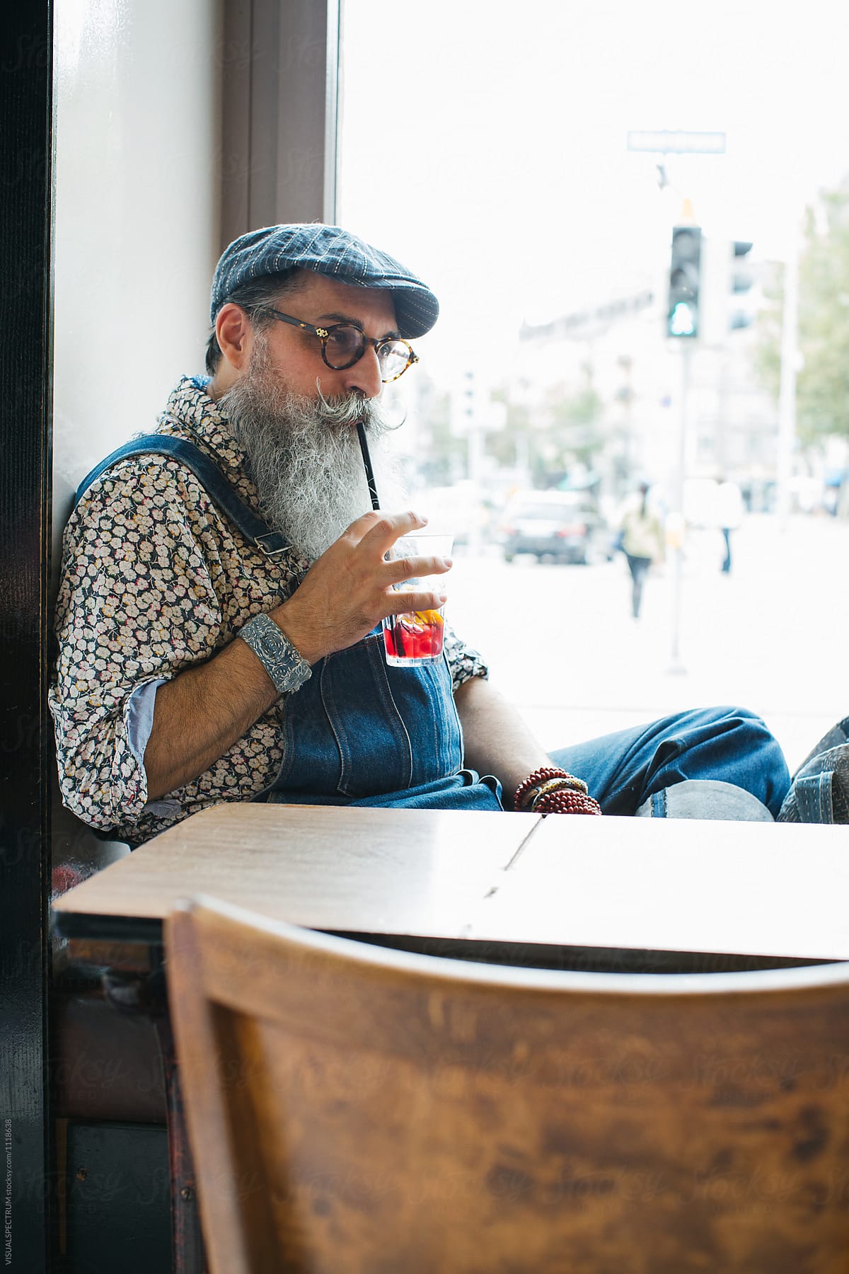 Indoor Portrait of Cool Elderly Male Hipster Drinking Ice Tea in Restaurant