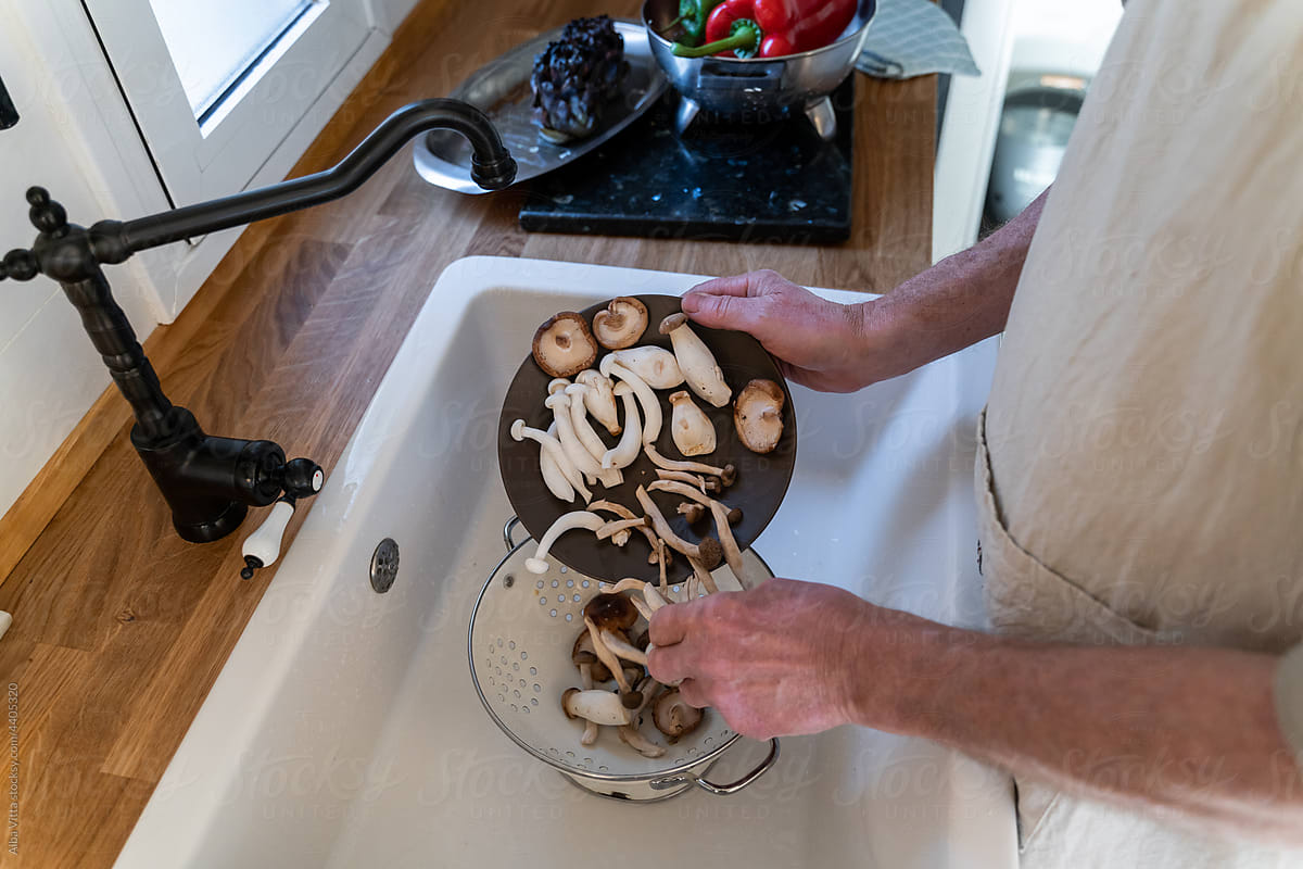 Senior man washing mushrooms at kitchen sink
