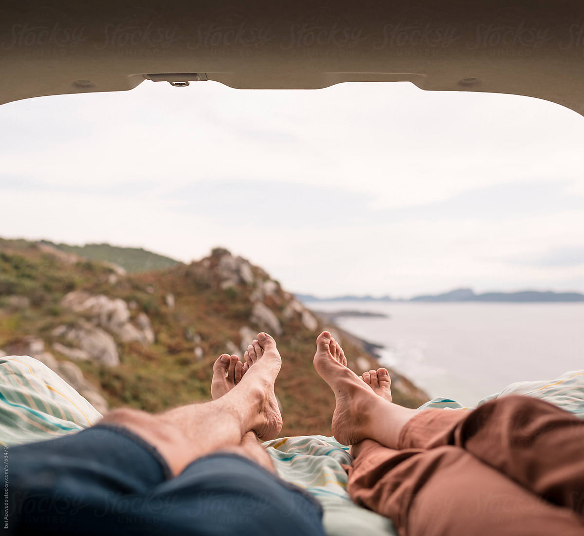 Couple legs resting on camper van bed with beautiful view