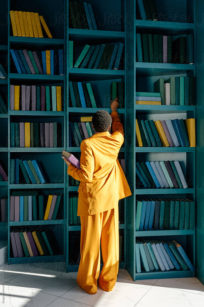 Woman in yellow outfit choosing books in library