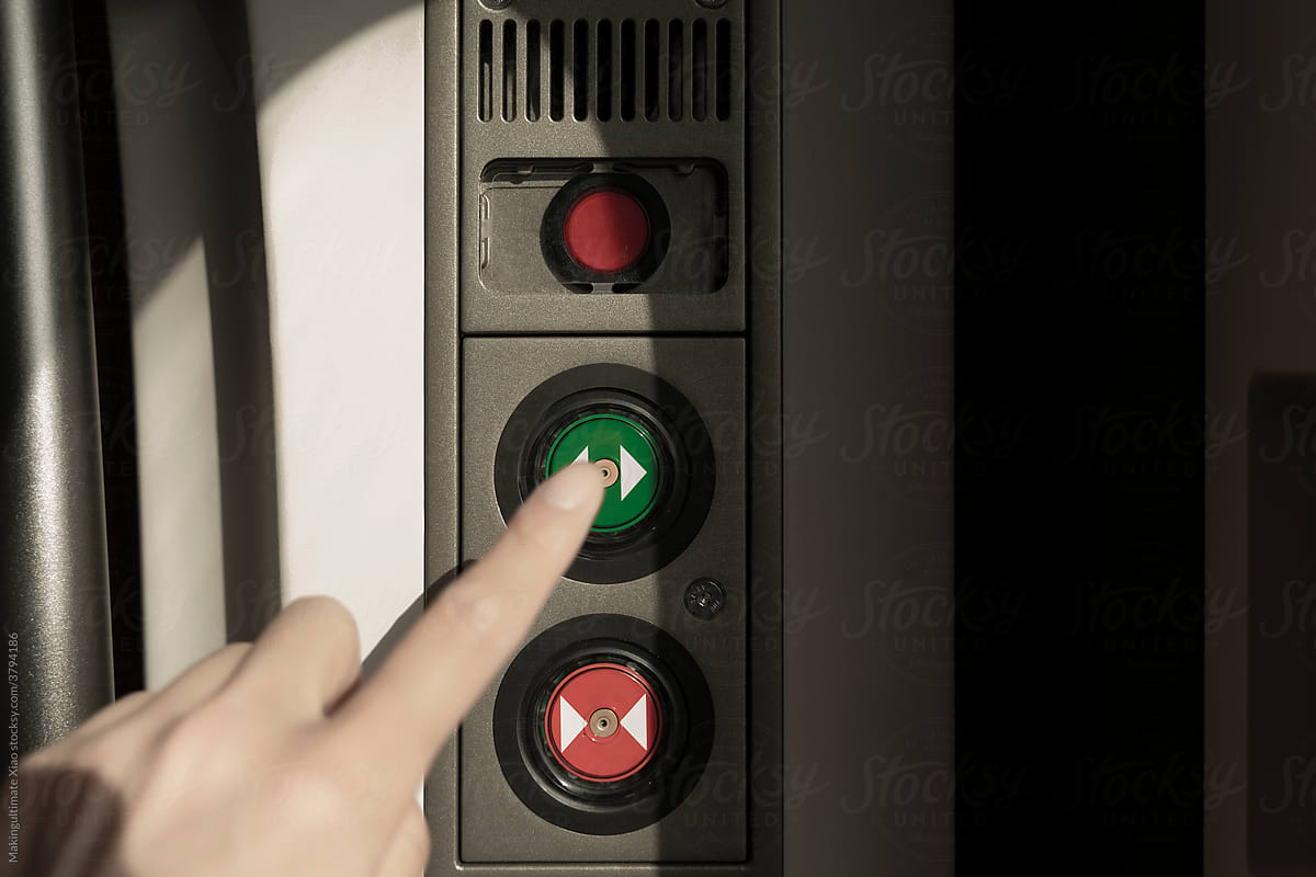 A man\'s hand is pressing the green button
