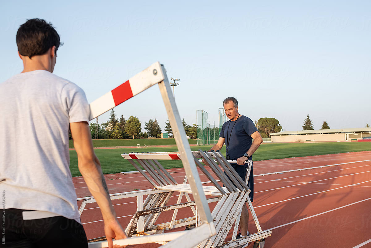 Athlete helping trainer to place hurdles