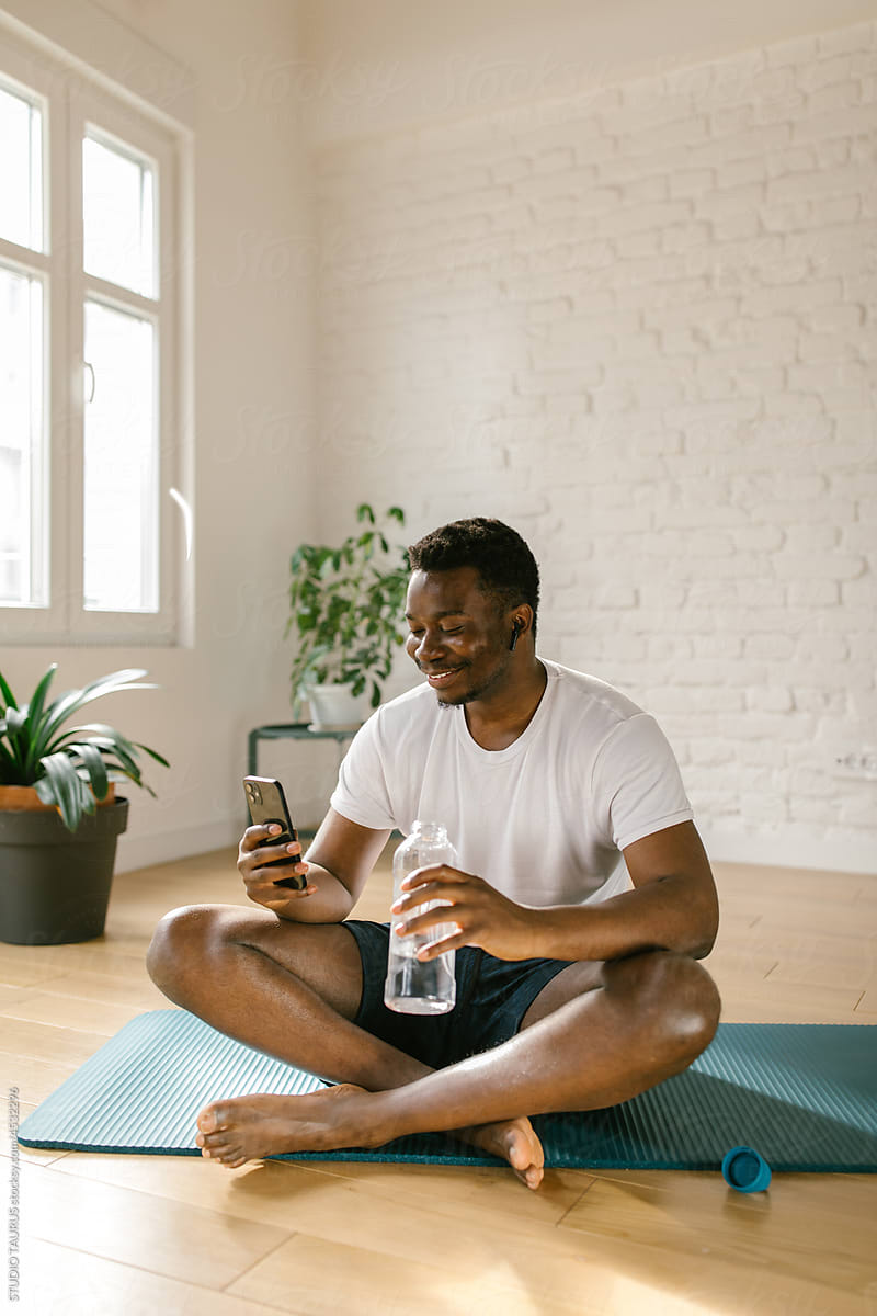 Smiling male using smartphone after home workout