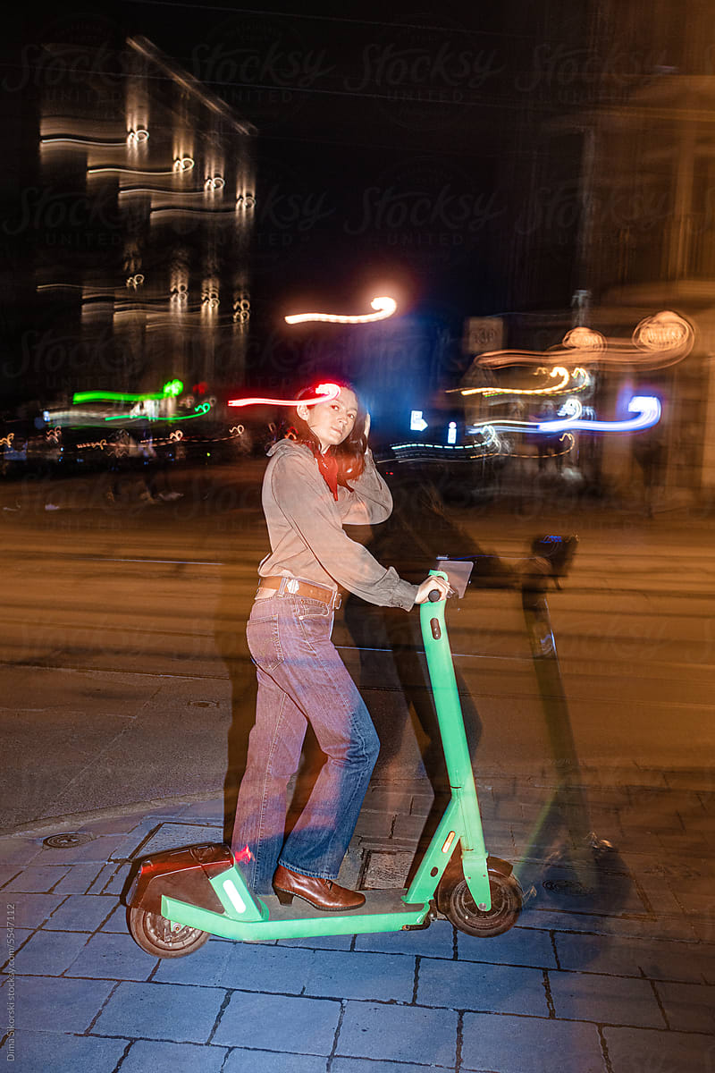 Portrait of a thoughtful girl on an electric scooter in a night city