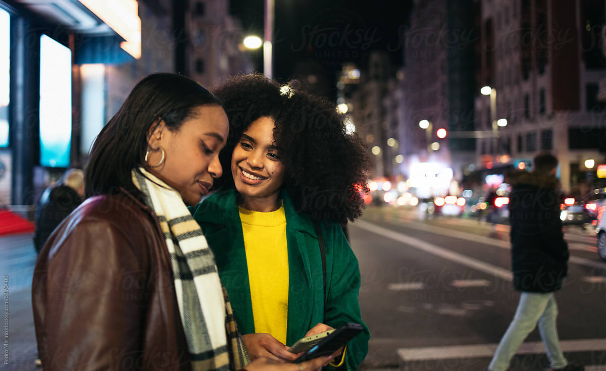 Young women waiting to cross a crosswalk in the city at night