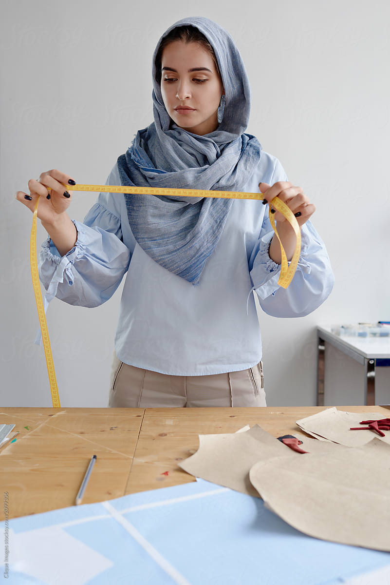 Woman tailoring with measure tape in atelier