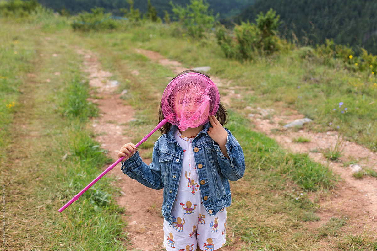 Joyful Little Girl Playing With Butterfly Net In meadow