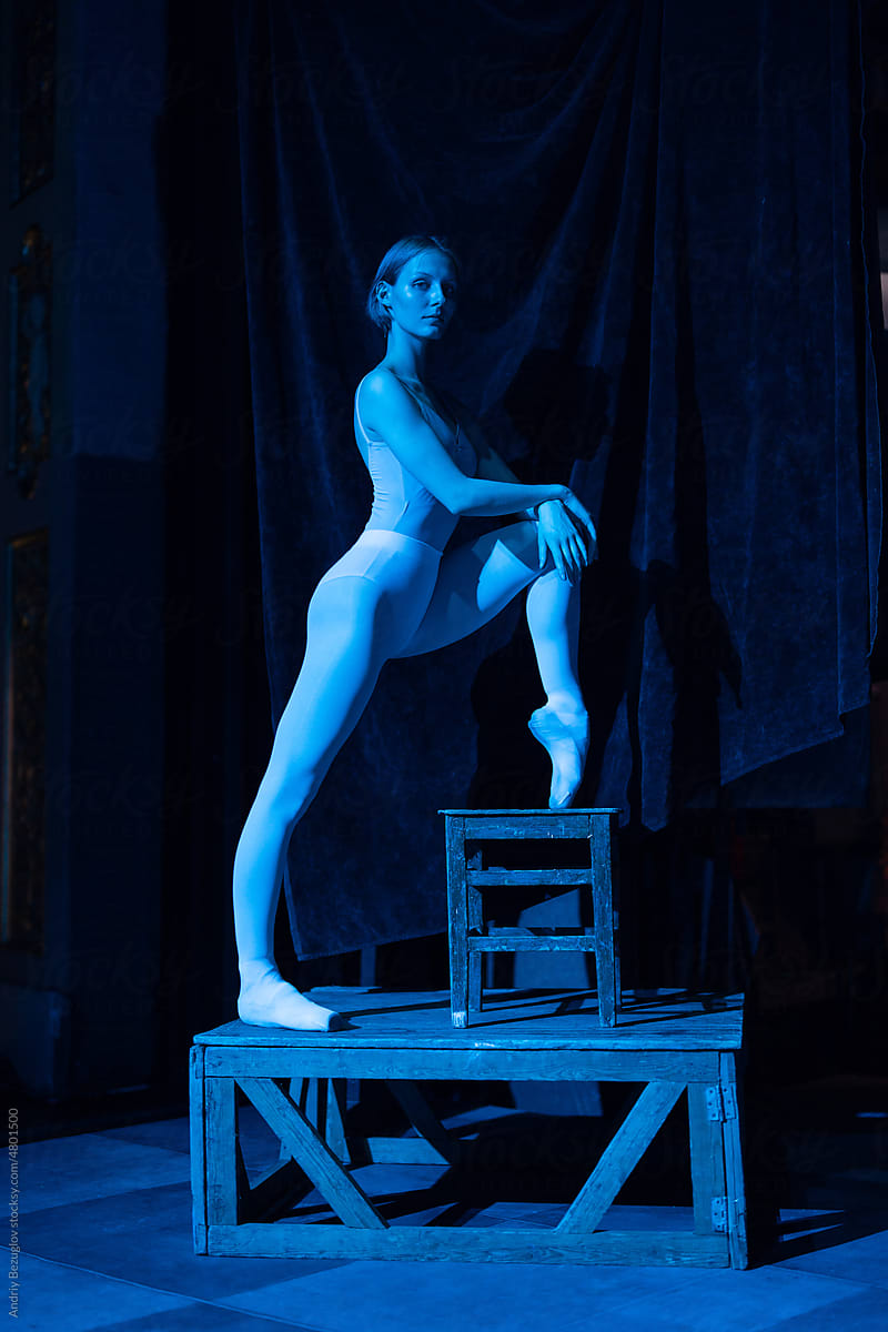 Blue light view of the young ballerina stands in pointe shoes