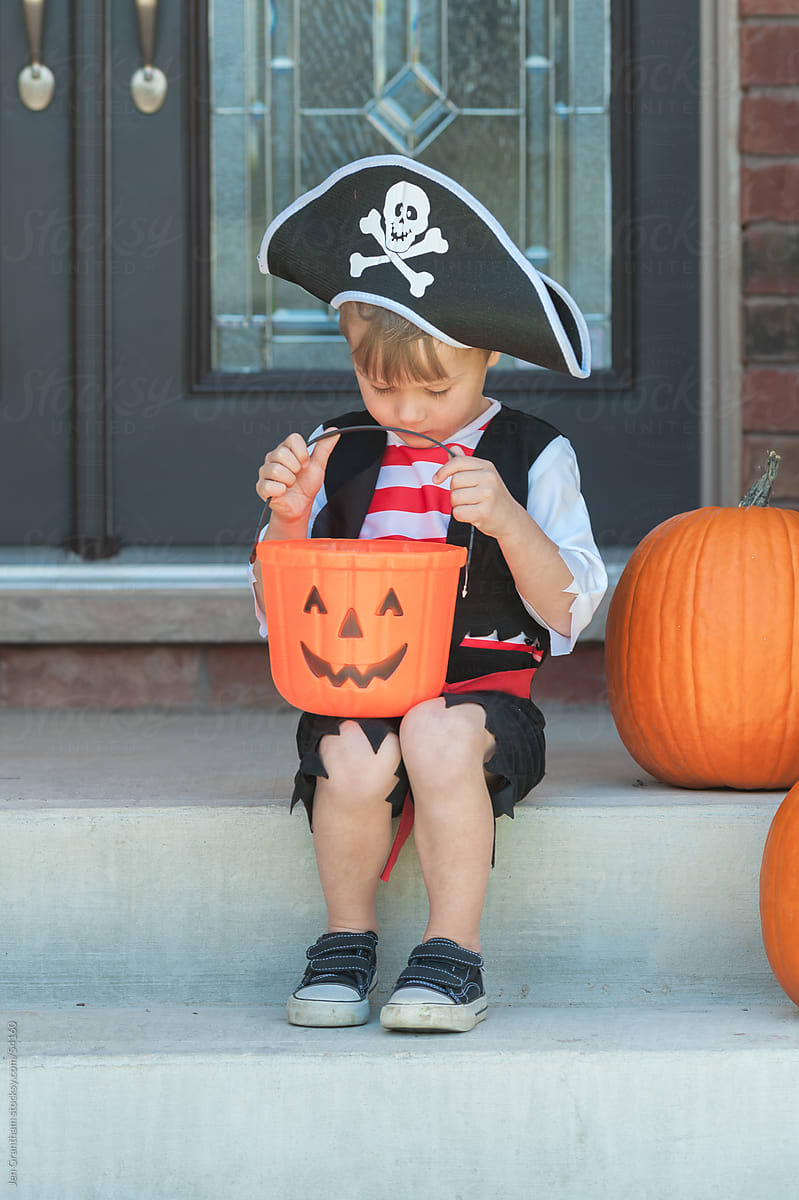 Toddler in pirate costume looking into candy bucket