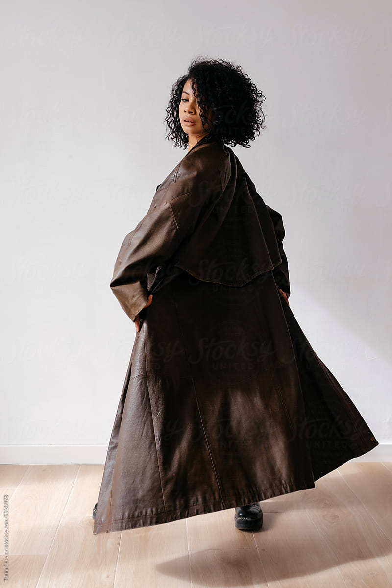 Black woman in brown leather coat turning around