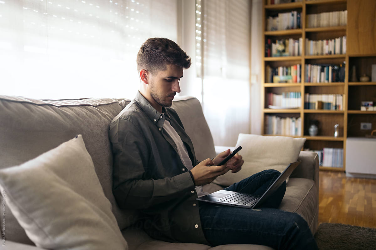 Young man using laptop and smartphone working remotely