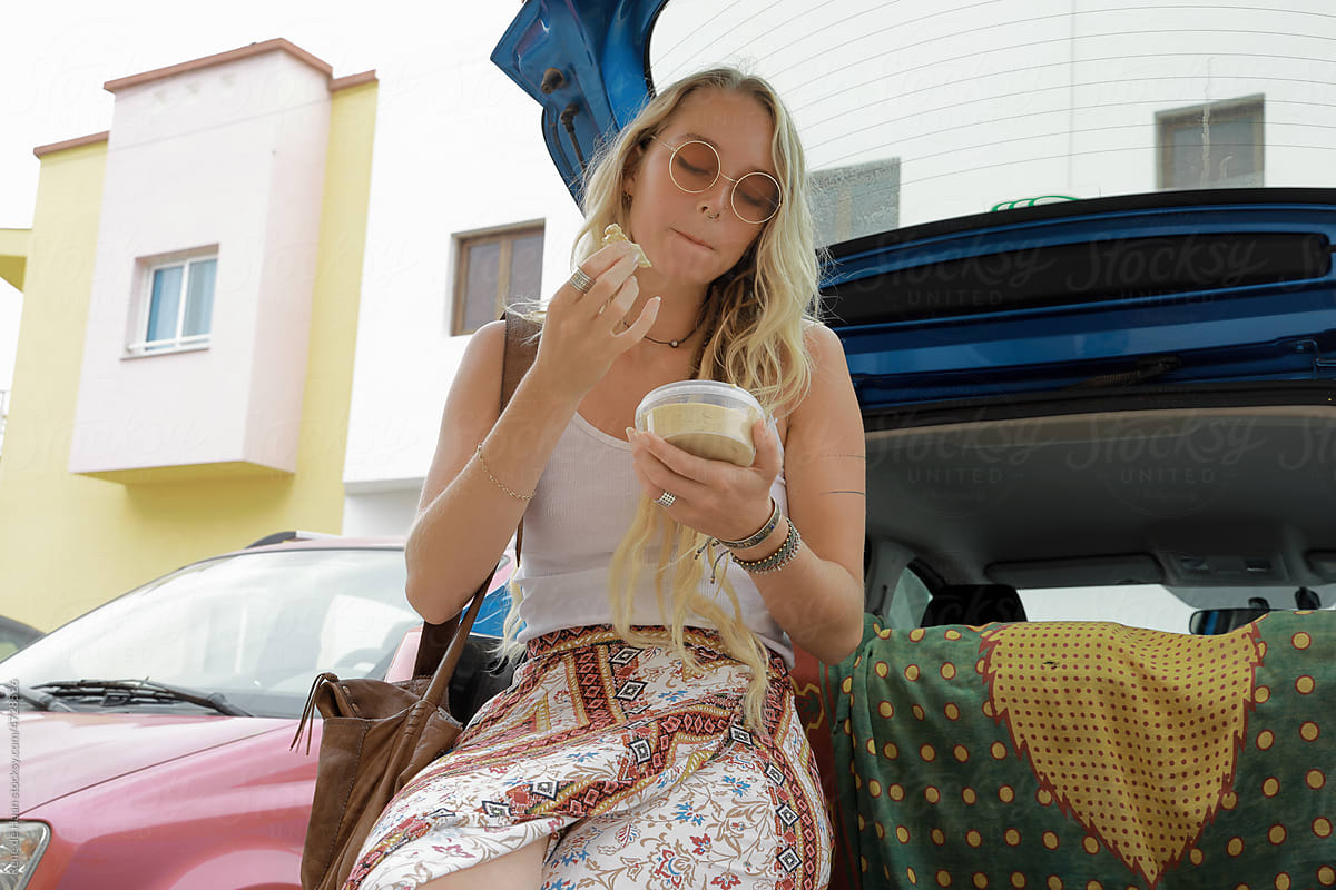 young woman eating lunch in car trunk