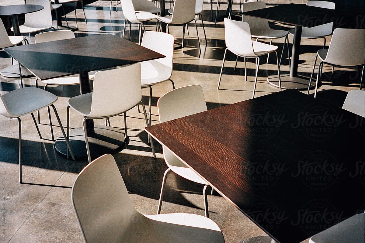 Empty White Chairs and Dark Wood Tables in Soft Warm Light