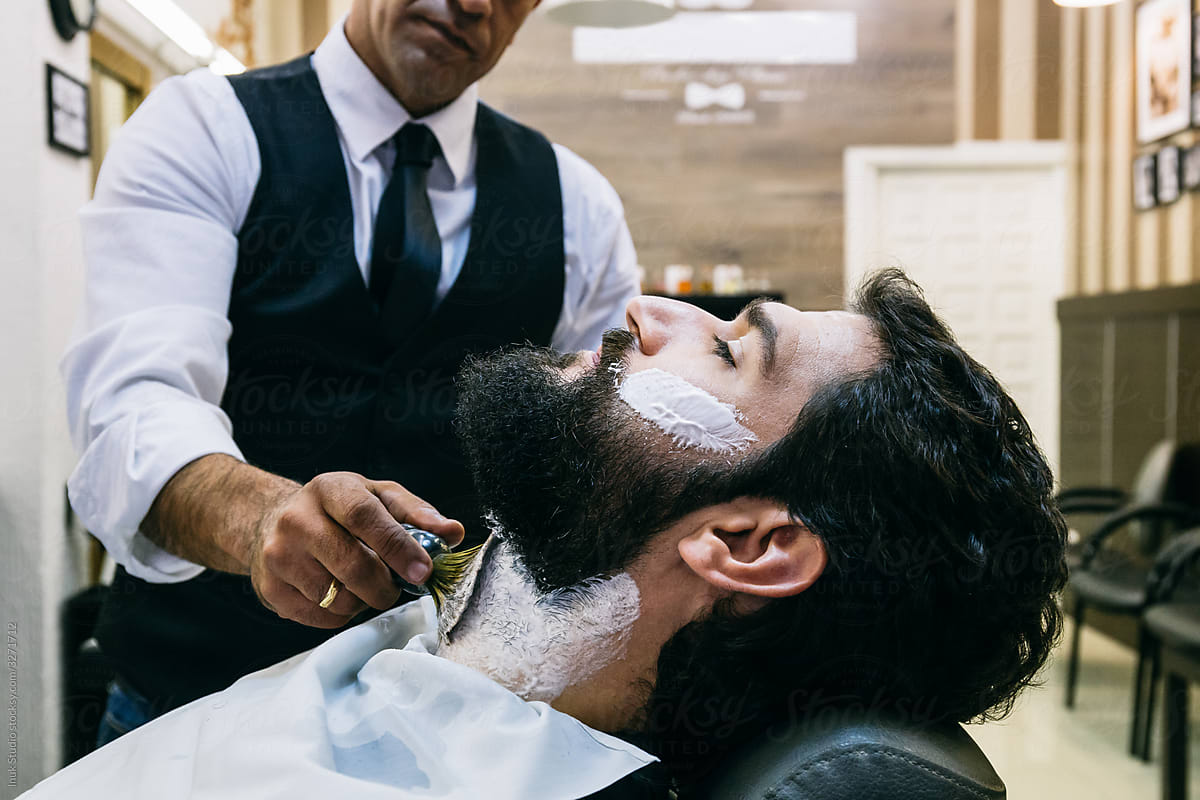 Customer in barbershop being shaved