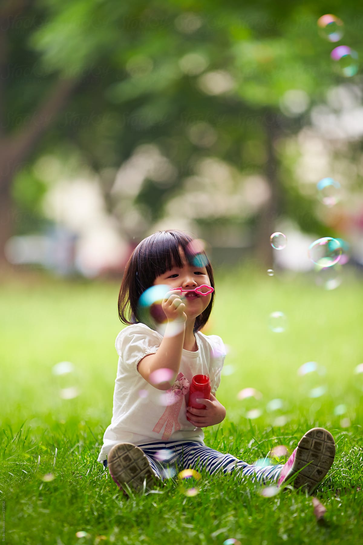 happy little  girl playing with soap bubble in the park